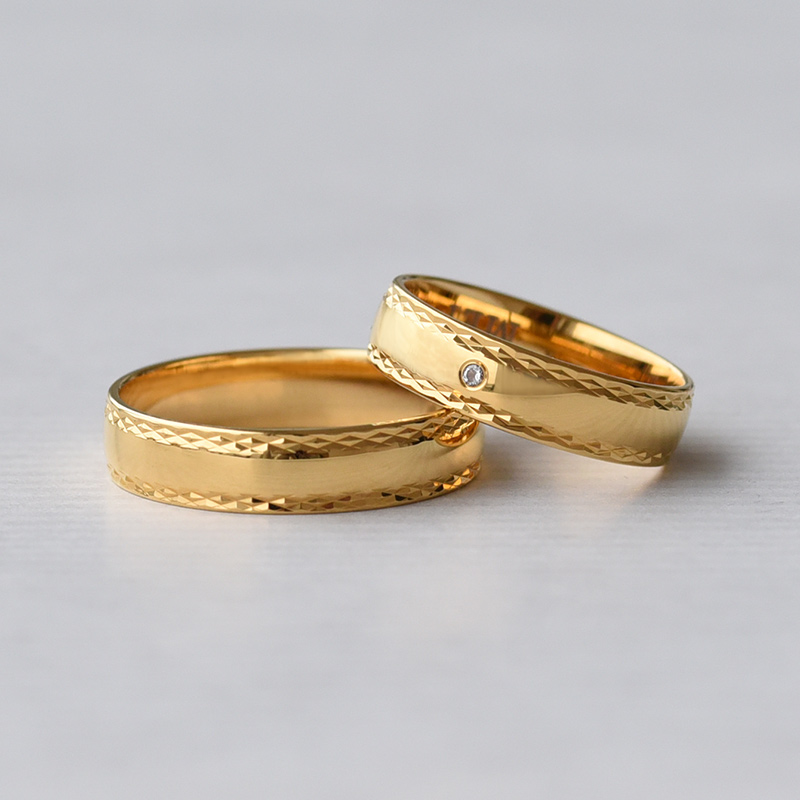 Zlaté snubní prsteny se zdobenými okraji a diamantem 